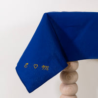 Donkerblauw tafellaken met de initialen geborduurd in de stof 