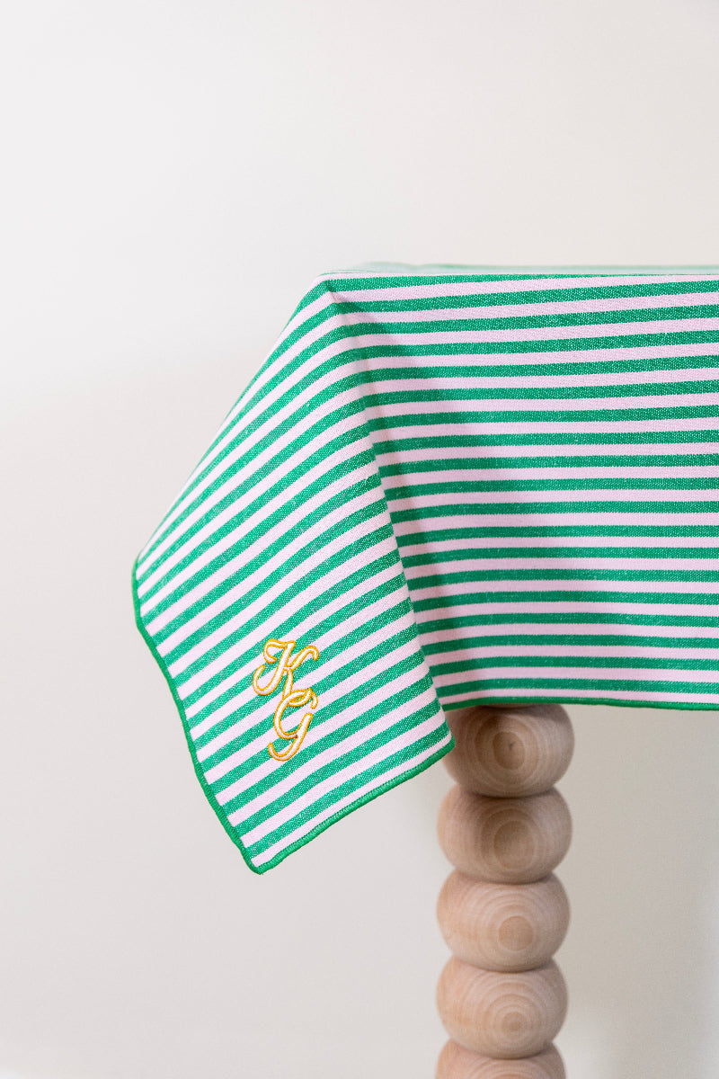 Frisgroen en poederroze gestreept tafelkleed, gepersonaliseerd met een monogram in crèmekleur en gouddraad