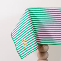 Frisgroen en poederroze gestreept tafelkleed, gepersonaliseerd met een monogram in crèmekleur en gouddraad