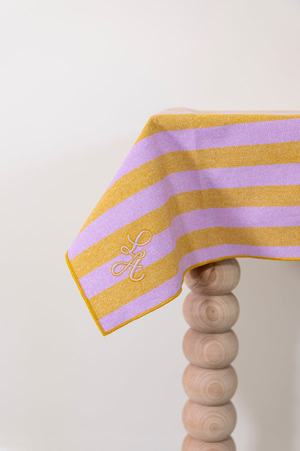 Gestreept tafelkleed in honingkleur en lila gepersonaliseerd met een monogram in lila en gouddraad geborduurd