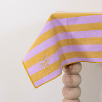 Gestreept tafelkleed in honingkleur en lila gepersonaliseerd met een monogram in lila en gouddraad geborduurd