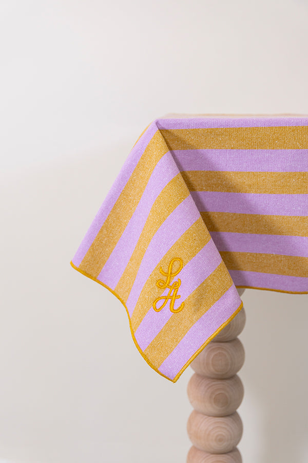 Gestreept tafelkleed in honingkleur en lila gepersonaliseerd met een monogram in gouddraad
