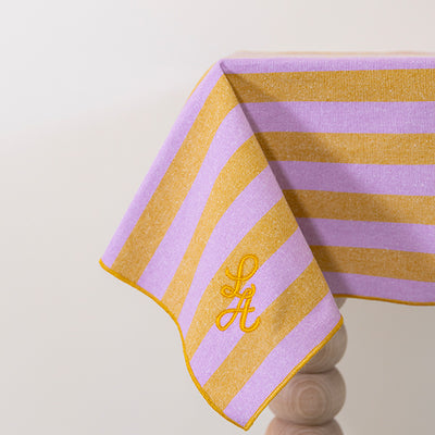 Gestreept tafelkleed in honingkleur en lila gepersonaliseerd met een monogram in gouddraad