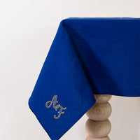 Koningsblauw tafelkleed gepersonaliseerd met een monogram in blauw en gouddraad