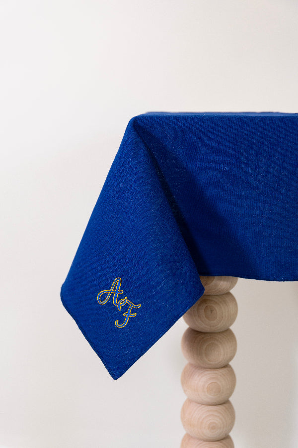 Koningsblauw tafelkleed gepersonaliseerd met een monogram in blauw en gouddraad