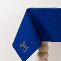 Koningsblauw tafelkleed gepersonaliseerd met een monogram in blauw en gouddraad
