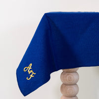 Koningsblauw tafelkleed gepersonaliseerd met een monogram in crèmekleur en gouddraad