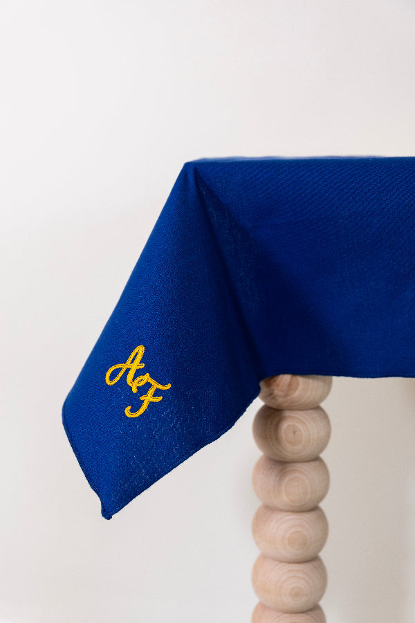 Koningsblauw tafelkleed gepersonaliseerd met een monogram in gouddraad