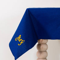 Koningsblauw tafelkleed gepersonaliseerd met een monogram in gouddraad