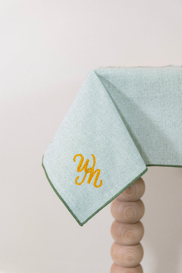 Olijfgroen tafelkleed gepersonaliseerd met een monogram in gouddraad
