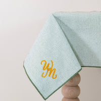 Olijfgroen tafelkleed gepersonaliseerd met een monogram in gouddraad
