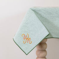Olijfgroen tafelkleed gepersonaliseerd met een monogram in roze en gouddraad