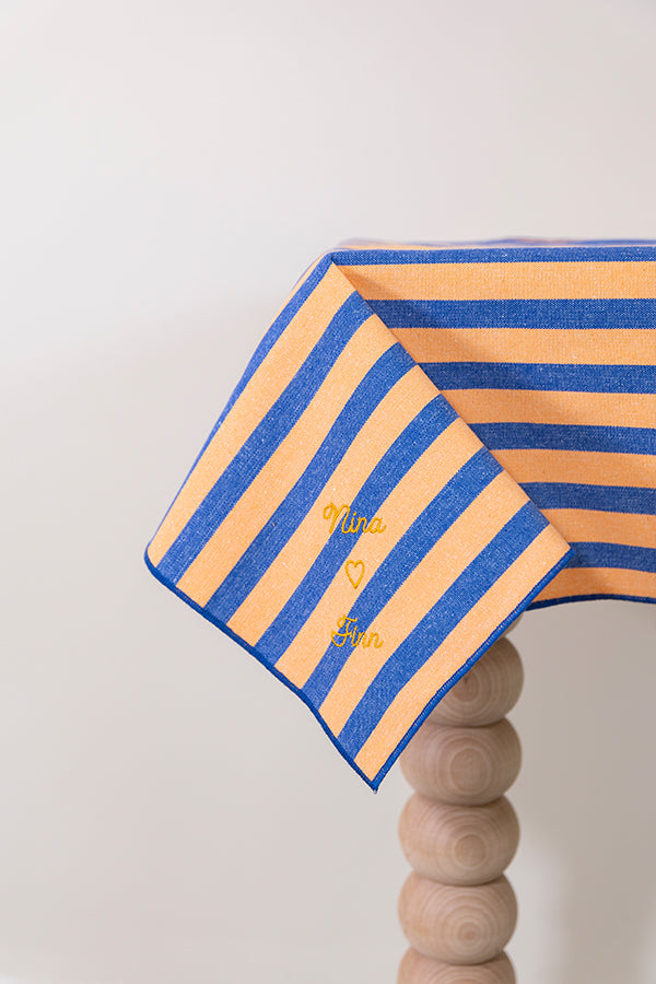 Oranje-blauw gestreept tafelkleed met de namen van het liefdeskoppel erin geborduurd met gouddraad