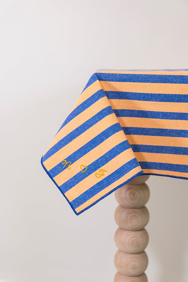Oranje-blauw gestreept tafellaken met de initialen geborduurd in de stof 