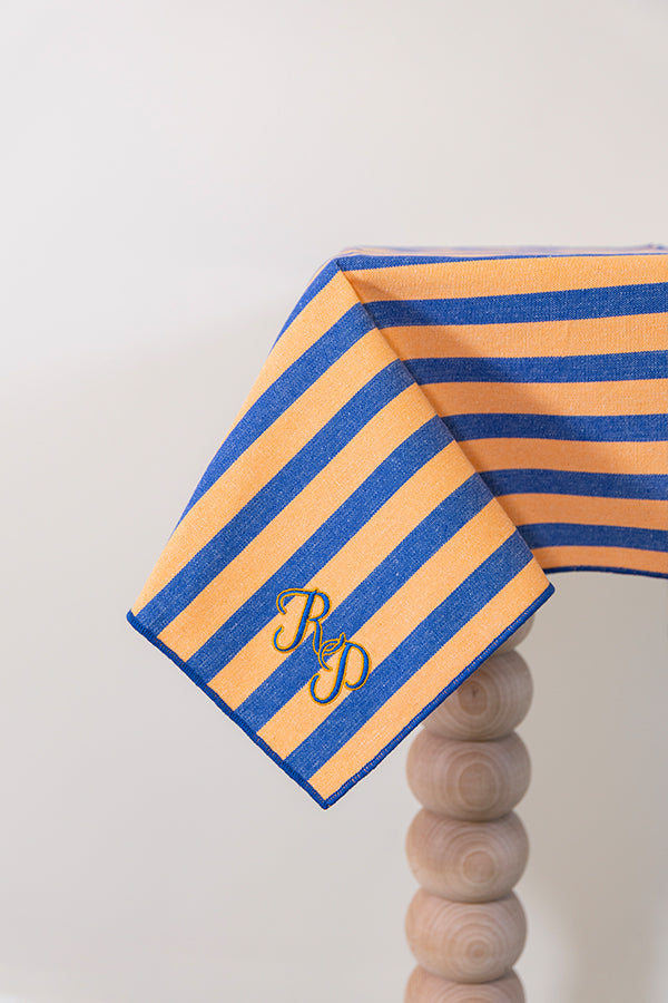 Oranje-blauw gestreept tafelkleed gepersonaliseerd met een monogram in blauw en gouddraad