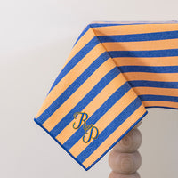 Oranje-blauw gestreept tafelkleed gepersonaliseerd met een monogram in blauw en gouddraad