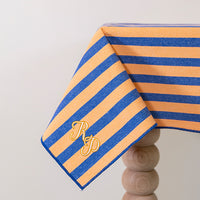 Oranje-blauw gestreept tafelkleed gepersonaliseerd met een monogram in crèmekleur en gouddraad
