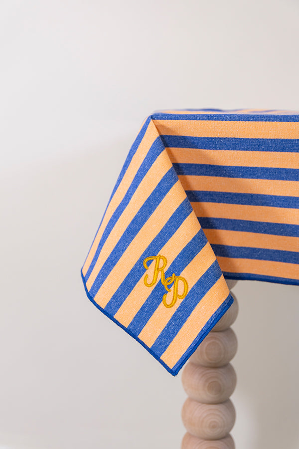 Oranje-blauw gestreept tafelkleed gepersonaliseerd met een monogram in gouddraad