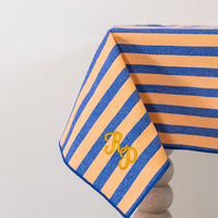 Oranje-blauw gestreept tafelkleed gepersonaliseerd met een monogram in gouddraad