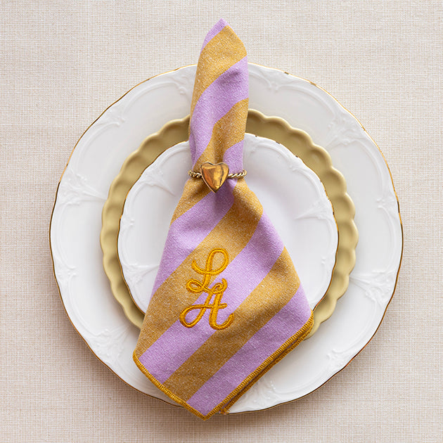 Servet van katoen in de kleur honing en lila, gepersonaliseerd met een monogram in gouddraad met een servetring