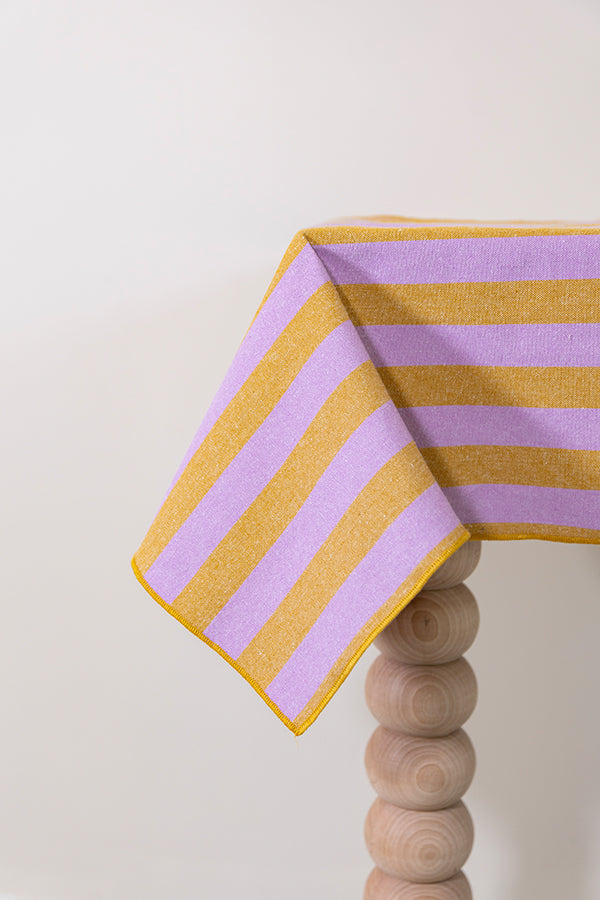 Gestreept tafelkleed in warmgele en zachtpaarse kleur prachtig afgewerkt met een geborduurde rand
