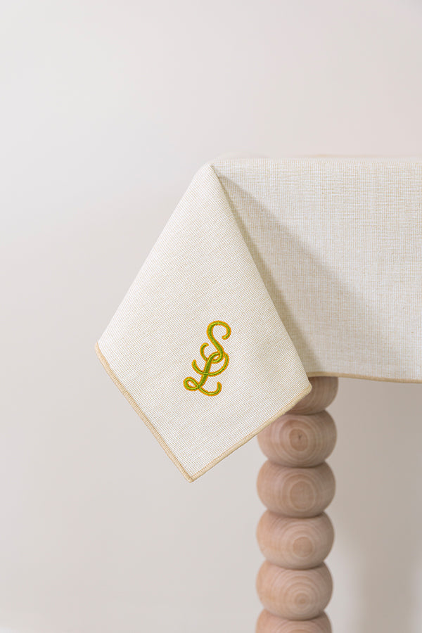 Zachtbeige tafelkleed gepersonaliseerd met een monogram in groen en gouddraad