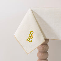 Zachtbeige tafelkleed gepersonaliseerd met een monogram in groen en gouddraad
